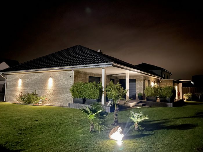 Bungalow bei Nacht mit Gartenbeleutung